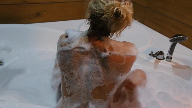 Beautiful blonde seductively teases her breasts in a bubble bath